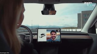 A person in a stationary Tesla vehicle taking a Zoom call.