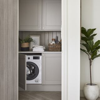 Grey utility room with shaker doors, washing machine and white walls.