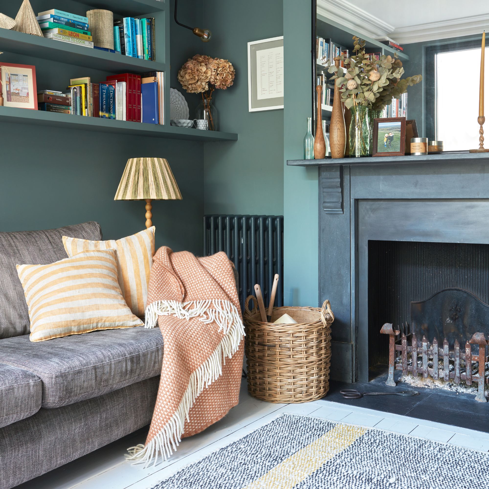 Teal painted living room with a black painted fireplace hearth and a grey sofa