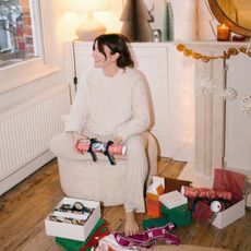 A woman on Christmas Day opening presents in the living room