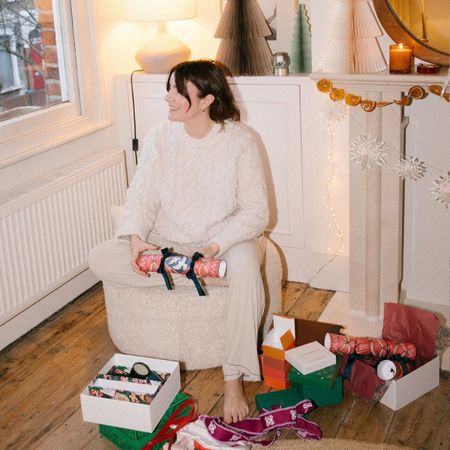 A woman on Christmas Day opening presents in the living room