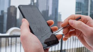 Moto G stylus with pen in hand in front of skyscrapers