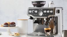 A Breville stainless steel coffee machine, along with chocolate muffins and an espresso.
