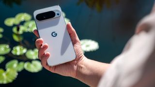 Holding a white Google Pixel 10 Pro XL in front of a pond filled with lily pads