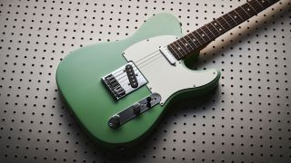 A Fender Player II Telecaster lying on a wooden board with holes in it