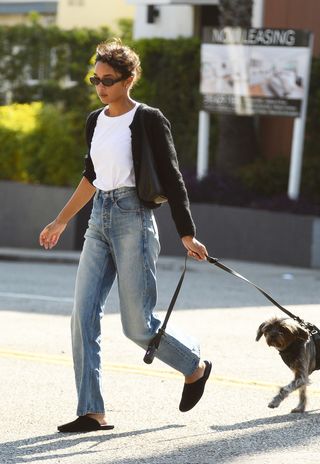 Laura Harrier wears a white tank top with jeans and a black cardigan.