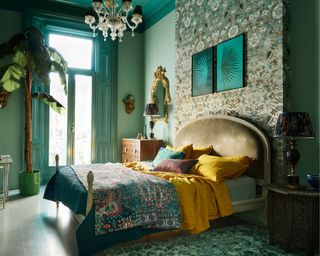 green maximalist bedroom with patterned wallpaper, colorful bedding and vintage decor