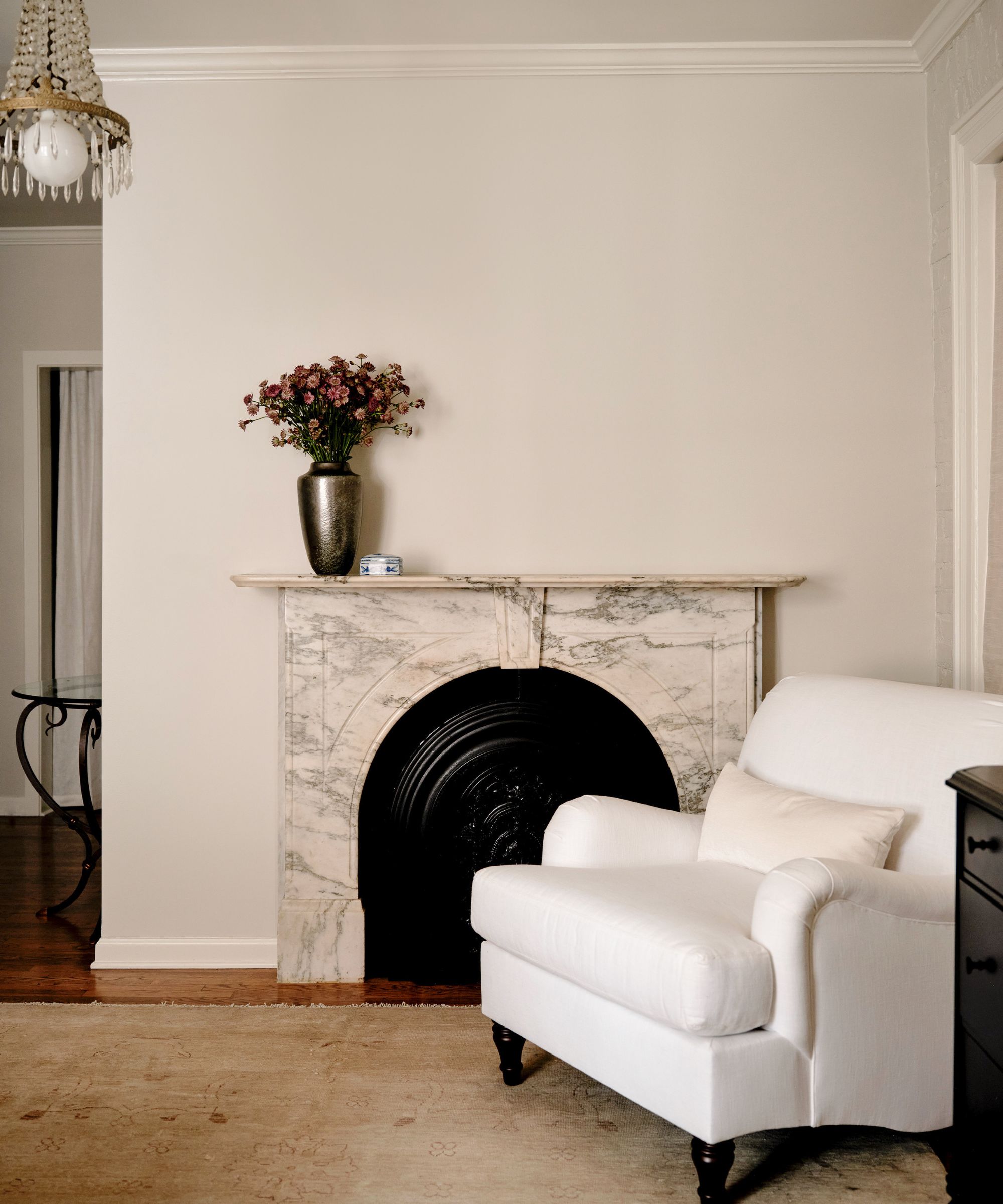 Cream living room with cream marble fireplace and a large white armchair