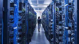 A woman cheerfully looking at some servers in a data center