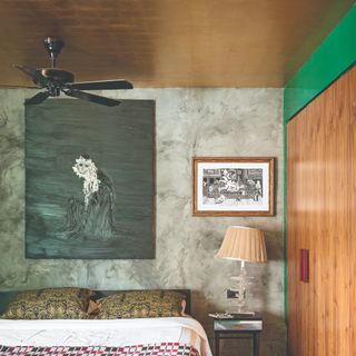 A bedroom with a gold wallpaper-covered ceiling and limewash-effect grey walls