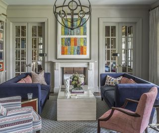 living room with navy blue sofas and bright artwork and white fire surround