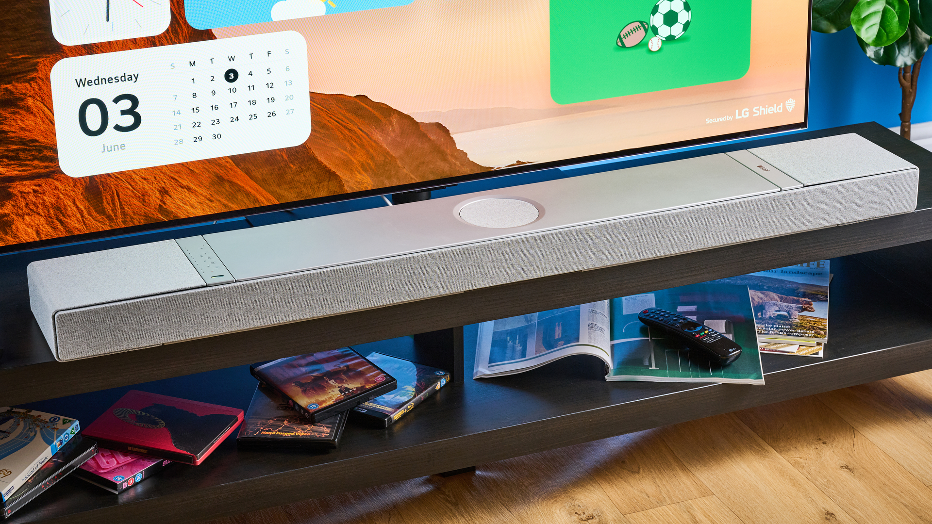 the KEF XIO soundbar in gray photographed with a TV and the Tom's Guide blue background