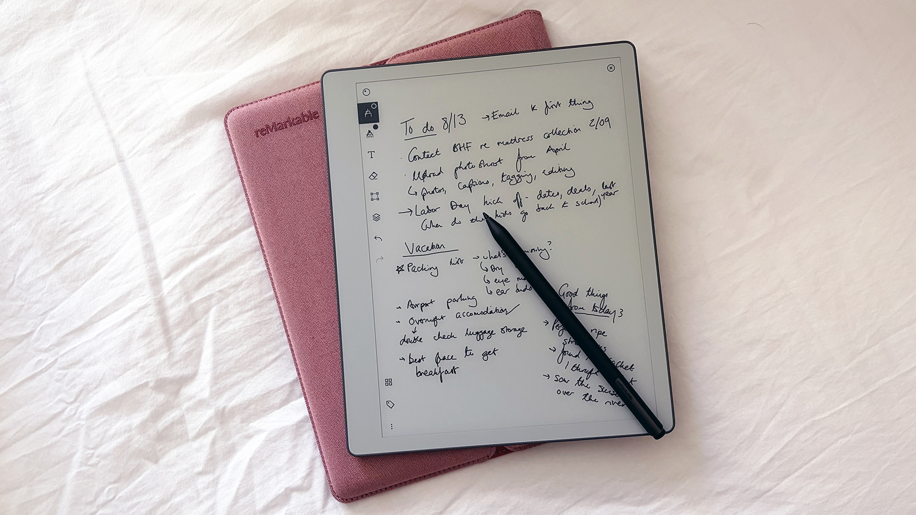A reMarkable Paper Pure tablet, stylus and pink case against a white bed sheet