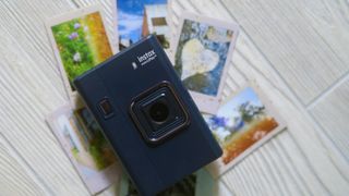 The Instax Mini LiPlay+ on a white wood background