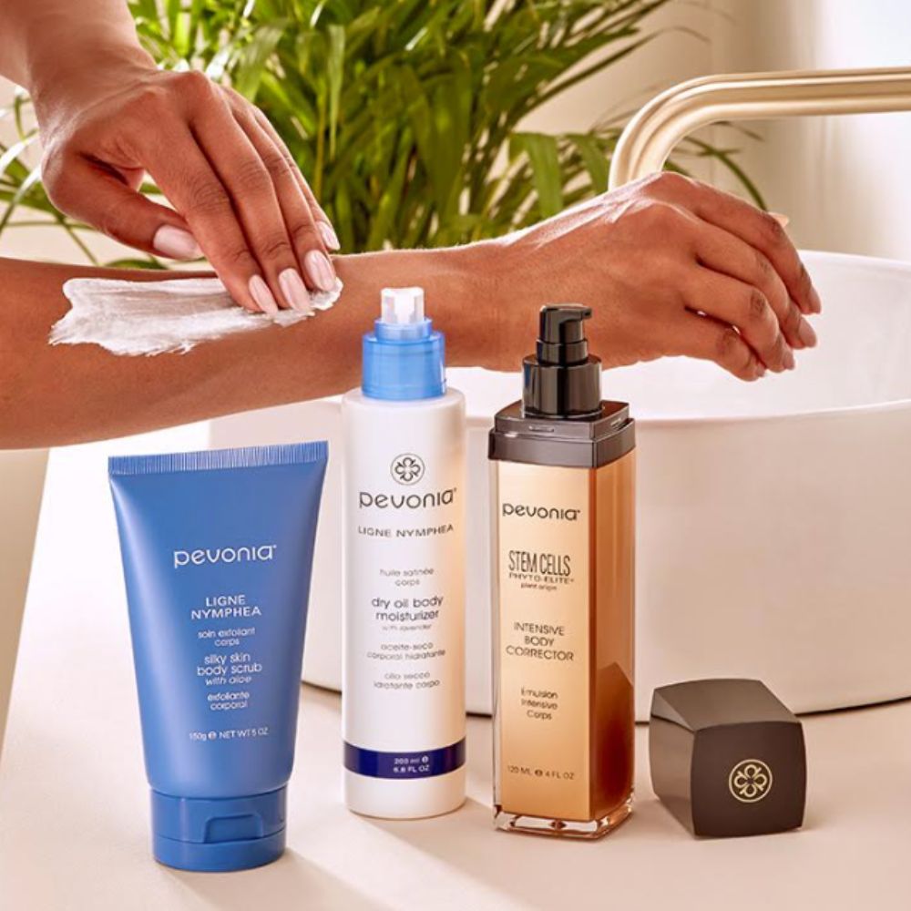 Woman washing her arm in bathroom, three Pevonia products lined up next to her.