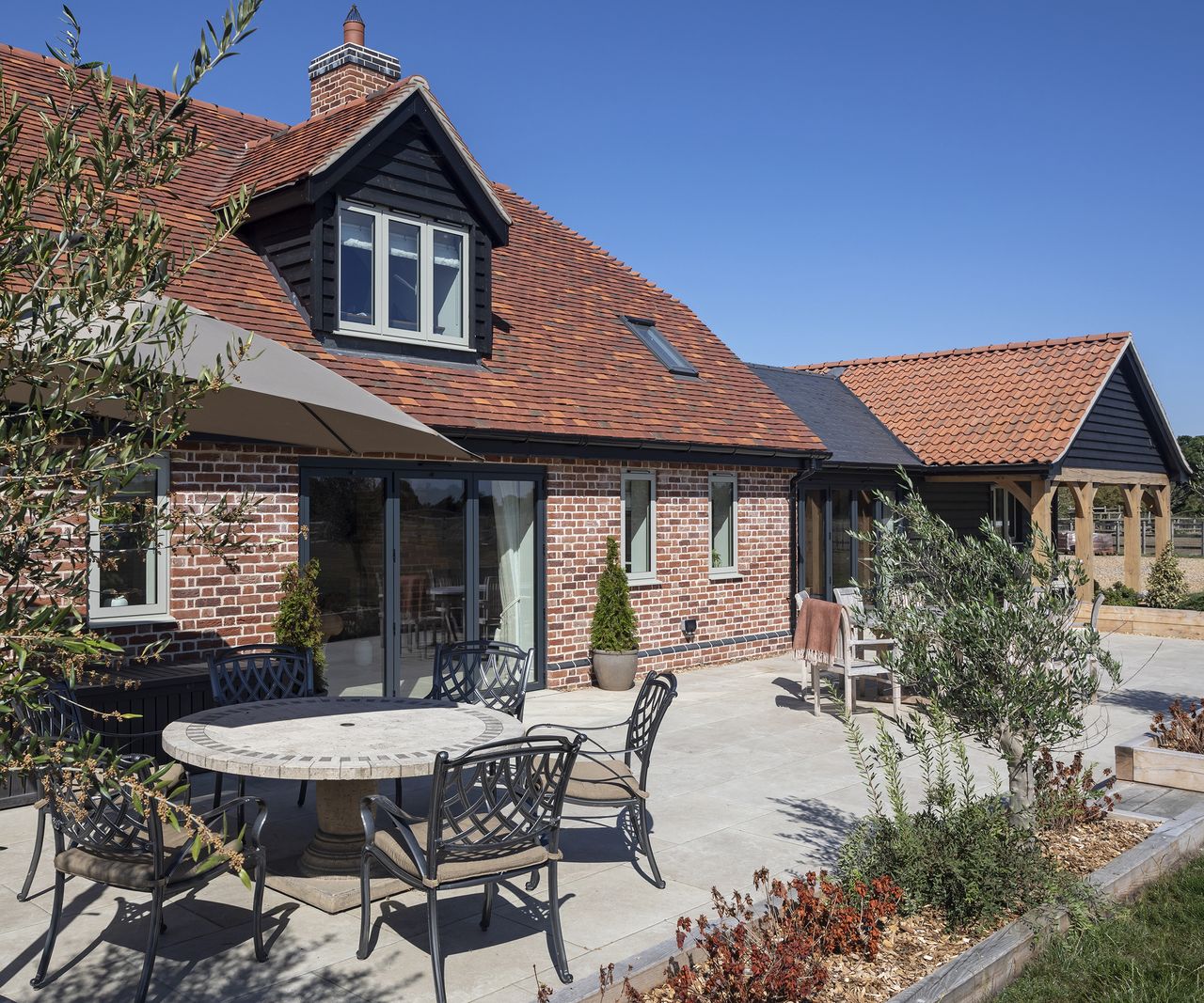 A sunny patio in front of a red brick home with a pitched roof