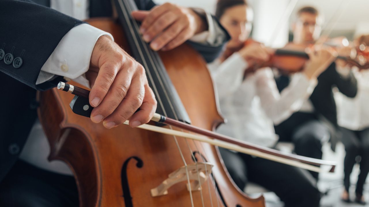 A cello players performs with an orchestra.