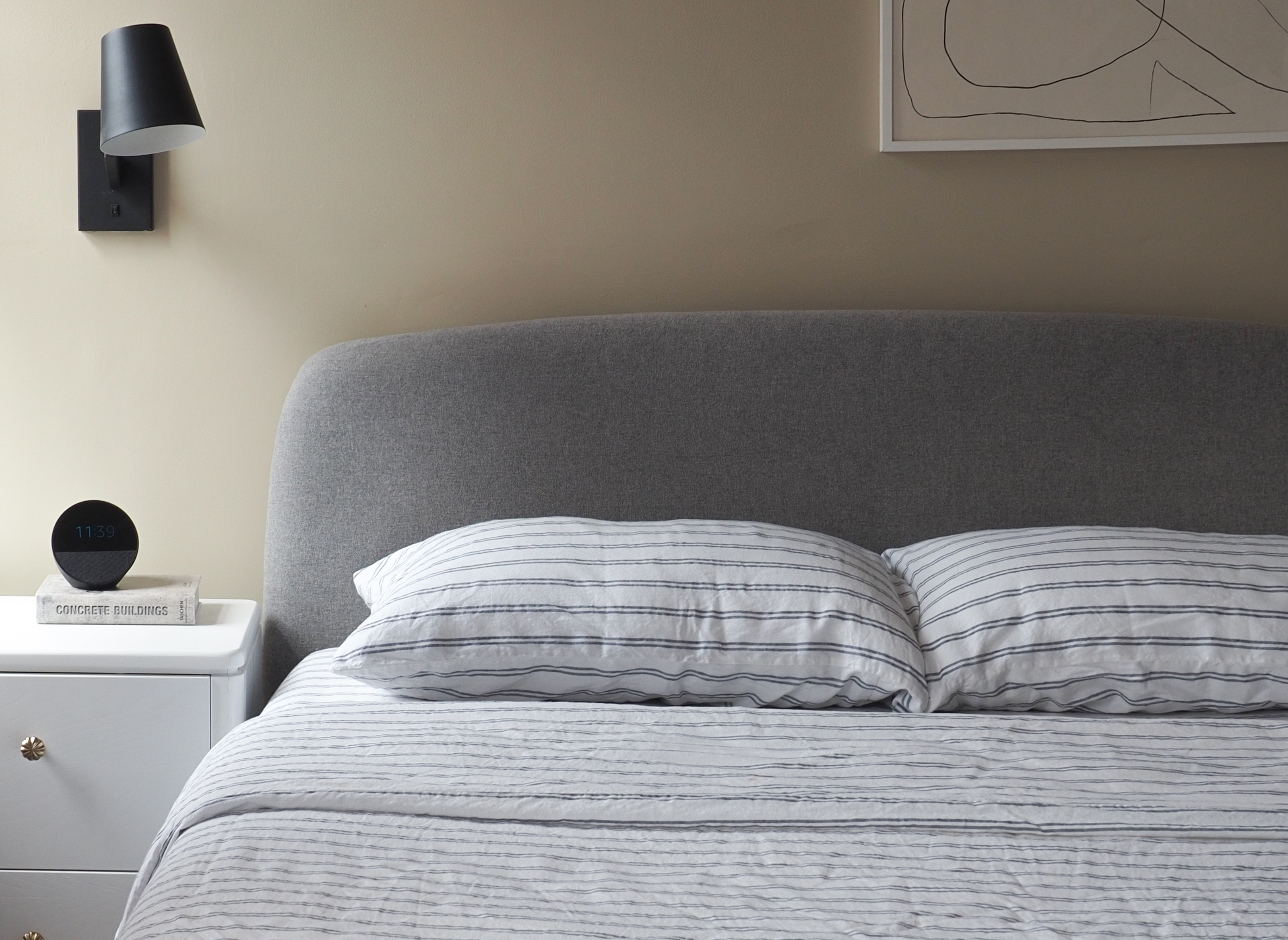 piglet in bed striped bedding on a grey bed in a beige bedroom 