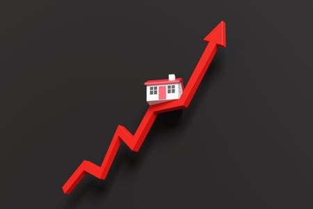 Toy house on a red up arrow on a black background.