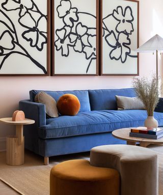 blue sofa with orange cushion and flower prints above