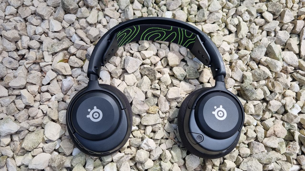 The SteelSeries Arctis Nova 5X Wireless, earcups facing down, on some attractive gravel