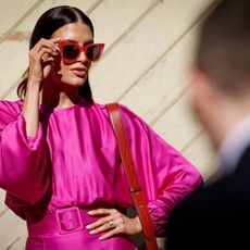 woman standing in the sun wearing a pink dress and sunglasses