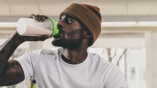 attractive man in beanie hat drinking a shake from a shaker bottle