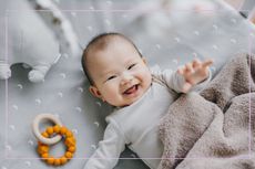 A smiling baby lying in a cot