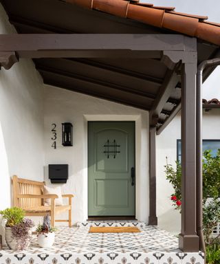 house exterior with white walls and soft green door and patterned tiles