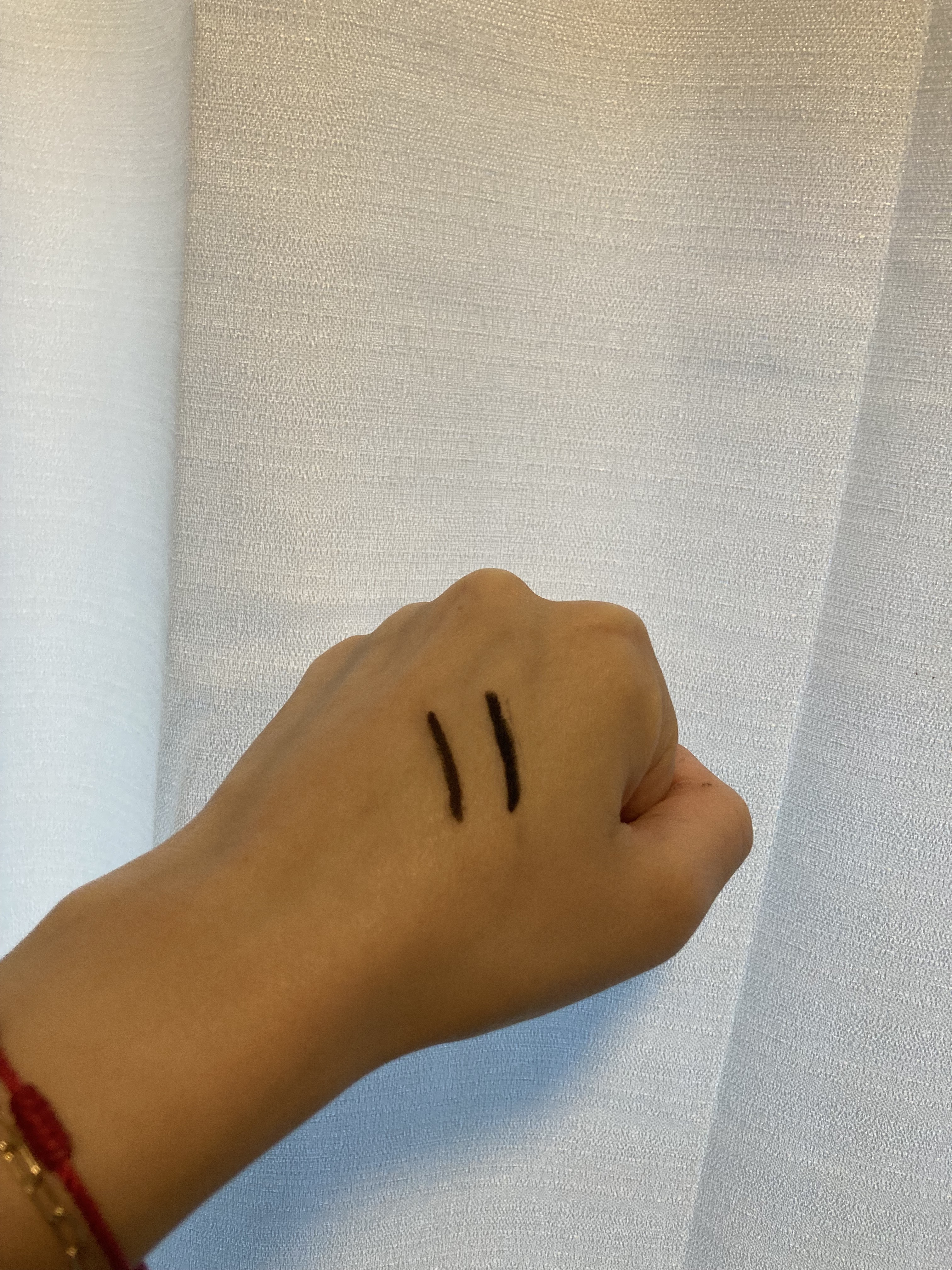 Black swatches of Neutrogena Smokey Kohl Eyeliner on back of hand