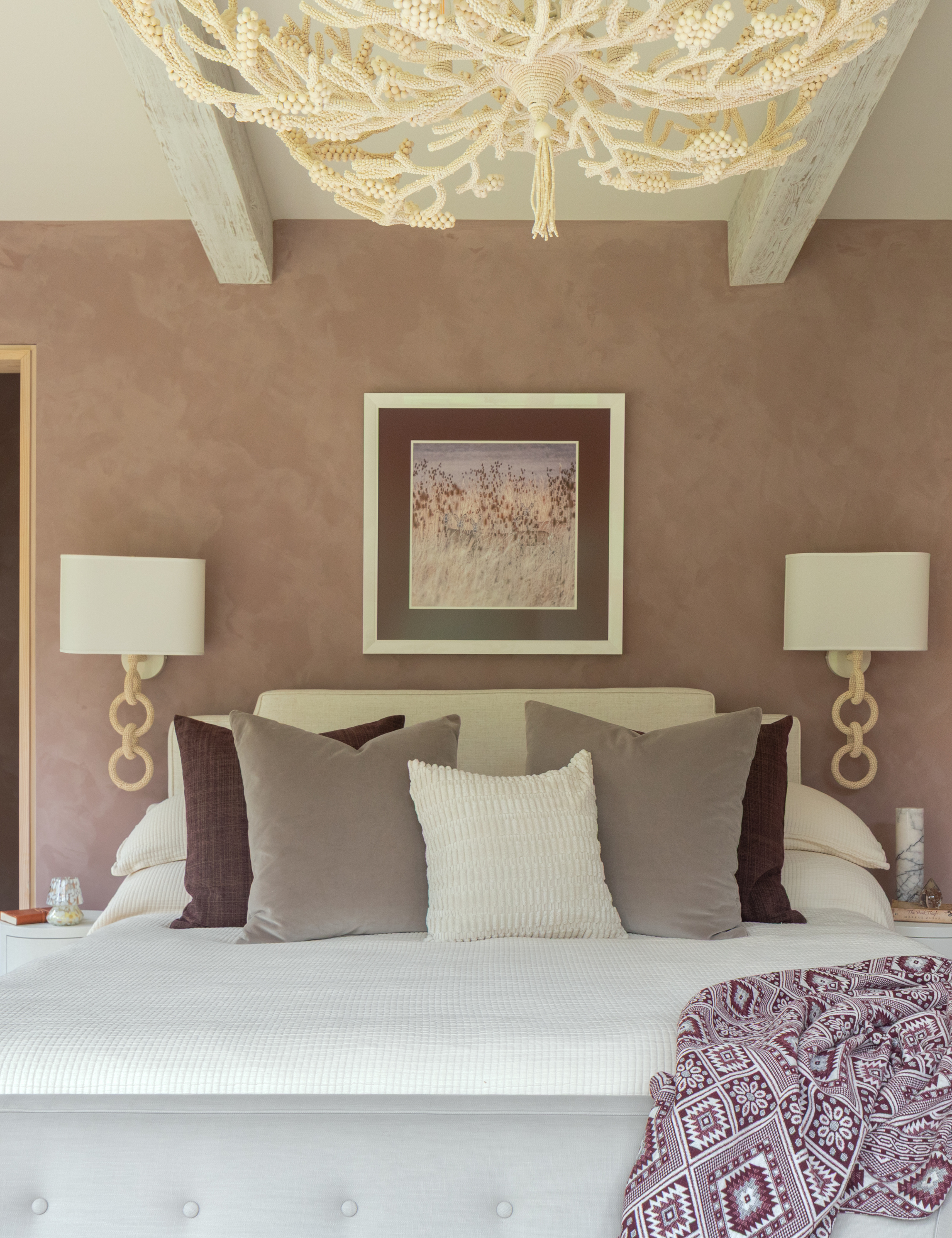 Mauve-walled, coastal-inspired bedroom featuring beaded nautical lamps and an lightweight linen throw pillows