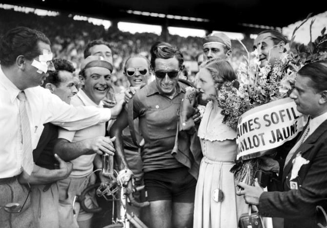 Italian Fausto Coppi (C) is congratulated upon his arrival, 24 July 1949 at the Parc des princes in Paris, after winning the Tour de France.