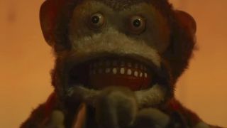 Close-up of stuffed monkey face with small eyes and lots of teeth in Oddity