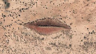 A satellite photo of a hill that looks like a pair of pink lips in the desert