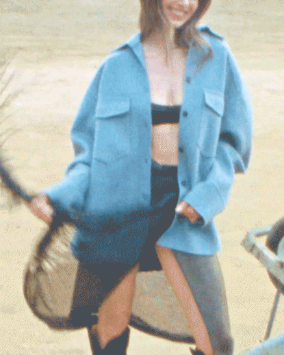a gif of alison brie twirling a black skirt wearing an oversized blue shirt over a black bra