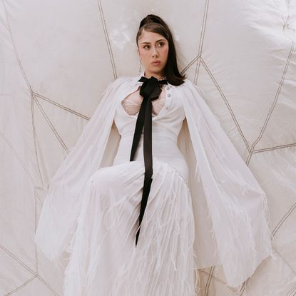 Kali Uchis posing against a cream fabric