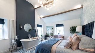 bath in bedroom against blue wall positioned at end of bed
