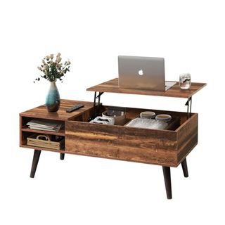 A wooden lift-top coffee table with items in it and a laptop on it