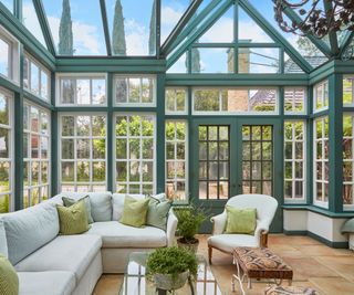 traditional conservatory-style solarium with glass walls and roof and white sofa