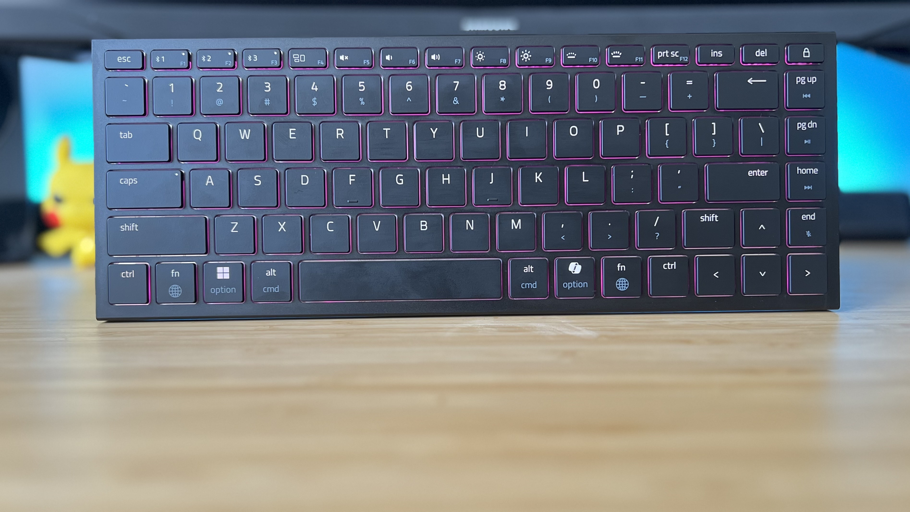 Razer Joro gaming keyboard on a wooden desk with blue backlighting