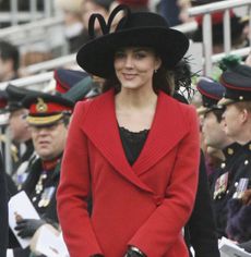 Kate Middleton wearing a red coat and black hat next to her parents