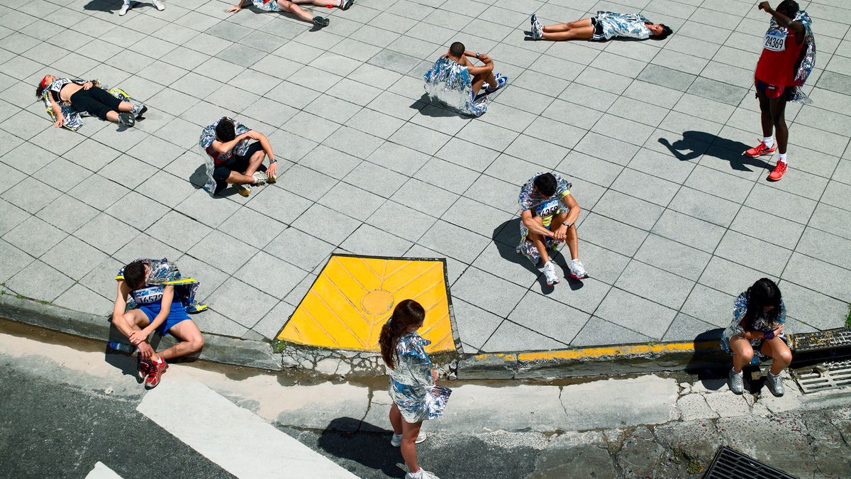 Marathon runners sitting and lying on sidewalk wrapped in foil blankets