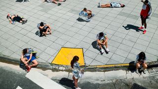 Marathon runners sitting and lying on sidewalk wrapped in foil blankets