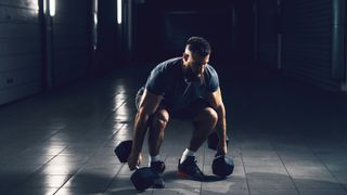 Man performs dumbbell squat in gym