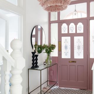pink front door in hallway with tiled flooring and black side table