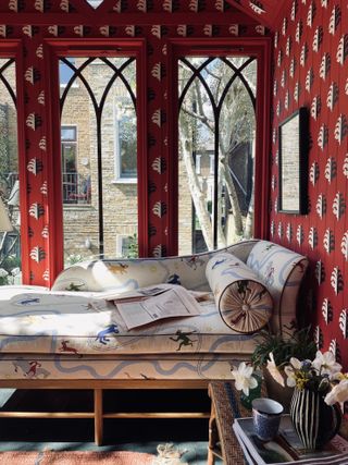 Chaise longue in red wallpapered garden room