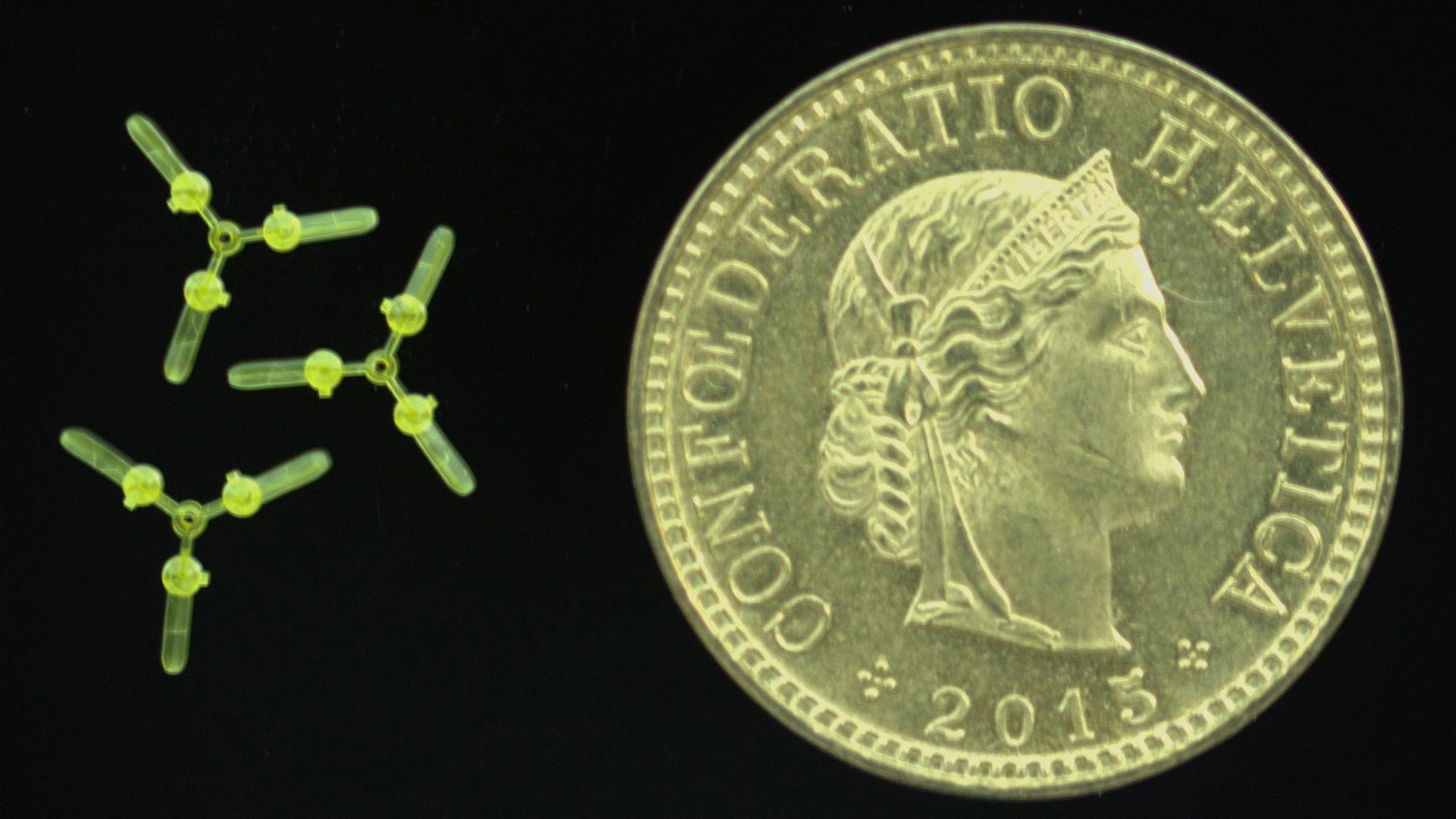 A close up of a gold coin with three y-shaped robots next to it.