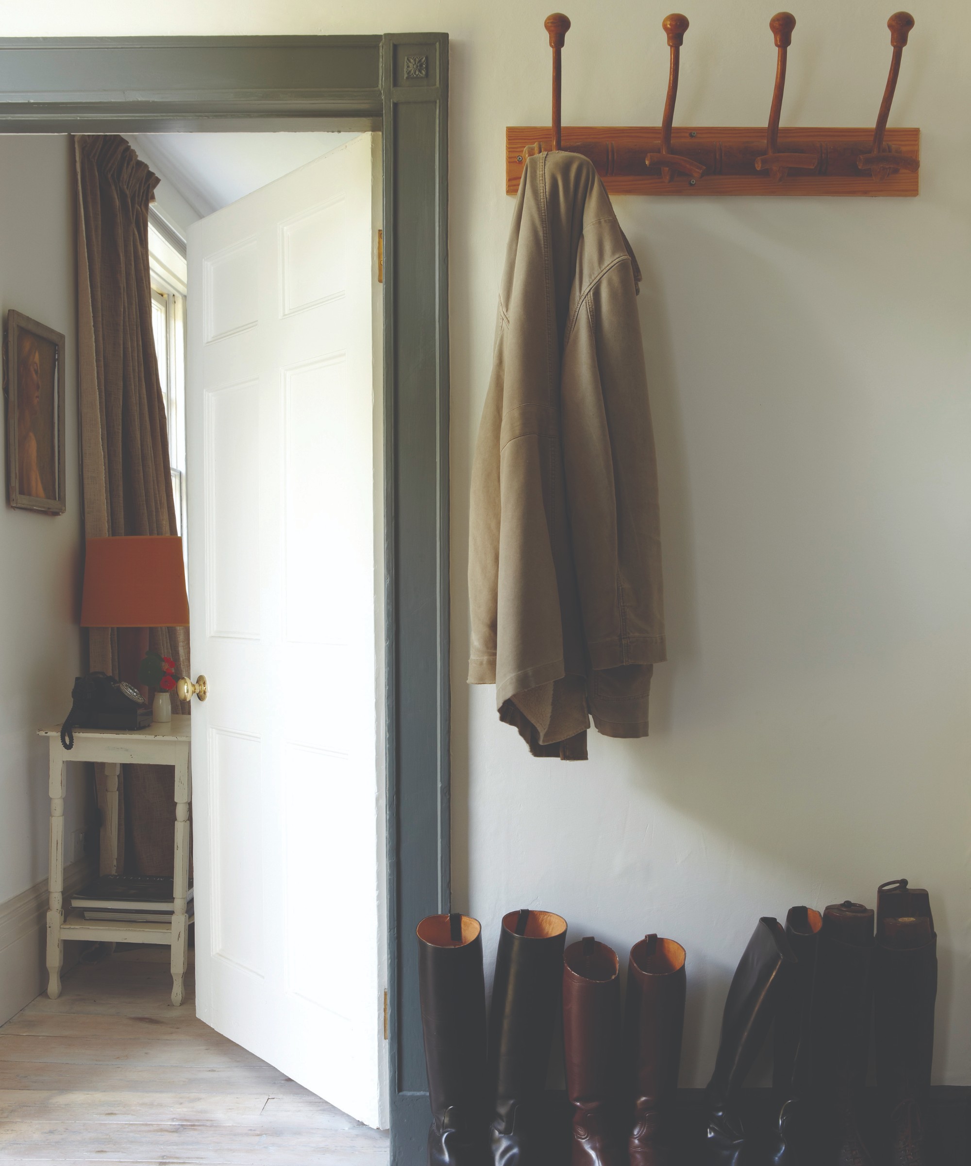 A hallway painted in Farrow &amp;amp; Ball's Wimborne White shade with a contrasting door frame in Green Smoke