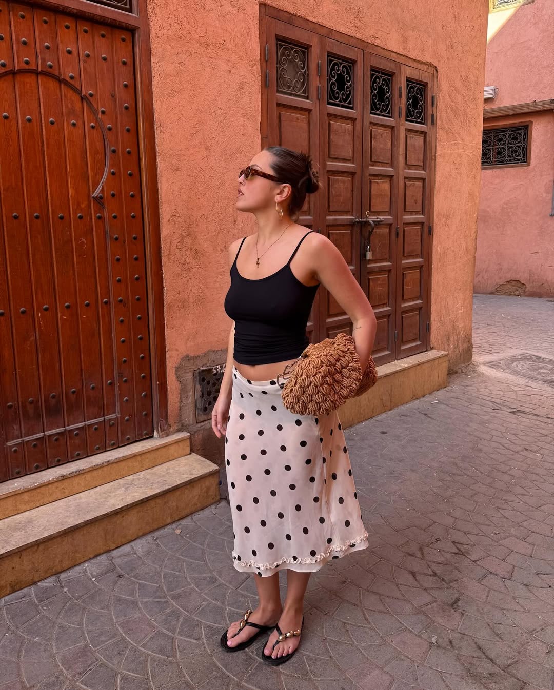 @oliviagraceherring wears a white-and-black polka skirt with a black tank and flip-flops