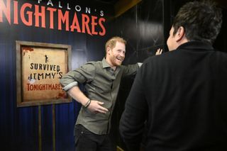 Prince Harry wearing a green shirt and laughing at Jimmy Fallon's haunted maze